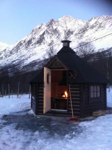 a small cabin in the snow with a fire in it at Kjelkebakken gård 2. in Lyngseidet +1 photo