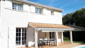 a white house with a table and a shed at Maison ruisseau l'eau blanche in Léognan