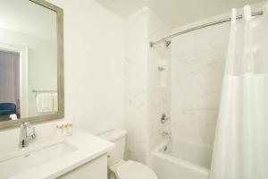 a white bathroom with a toilet and a sink and a shower at Sonder The Saddlery in Nashville