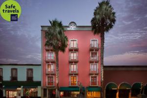 a pink building with two palm trees in front of it at Hotel MX garibaldi in Mexico City