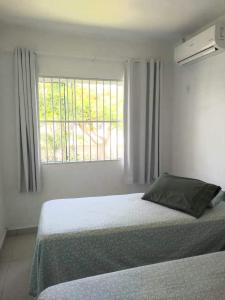 um quarto branco com uma cama e uma janela em Casa de praia na Gamboa - Garopaba SC em Garopaba