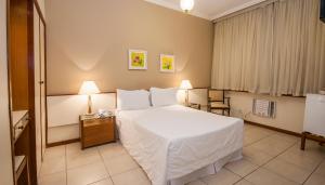 Habitación de hotel con 1 cama blanca y 2 lámparas en Rede Andrade Canada, en Río de Janeiro