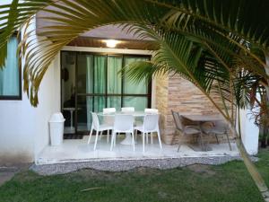 eine Terrasse mit einem Tisch, Stühlen und einer Palme in der Unterkunft ILOA Residence Apt Completo in Barra de São Miguel