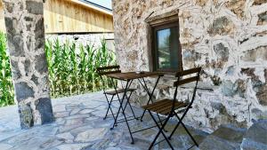 two chairs and a table in front of a stone building at Dedehan Retreat Otel in Muğla