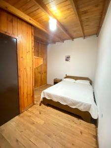 um quarto com uma cama branca e pisos em madeira em Hostal Traveland em Pichilemu