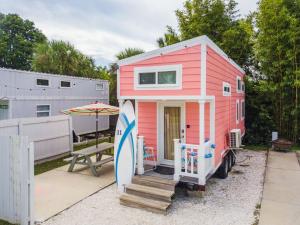 a pink tiny house with a surfboard next to a table at Tiny House Siesta in Sarasota