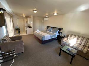 ein Hotelzimmer mit einem Bett und einem Sofa in der Unterkunft Delago Motel/Apartments in Christchurch