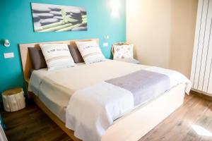 um quarto com uma cama grande com lençóis brancos e almofadas em La cà dei ulif em Gardone Riviera