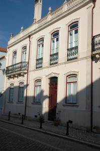 a white building with a red door on a street at Casa da Tia Guida in Golegã