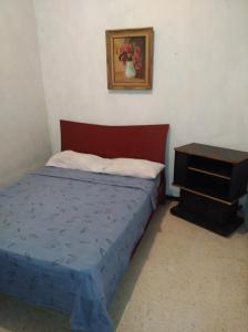 1 dormitorio con 1 cama y 1 mesa con un jarrón en la pared en Candida, en Caracas