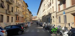 a narrow street with parked cars and motorcycles at Kos in Florence