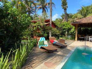 a patio with two chairs next to a swimming pool at Pousada Big Bambu in Trancoso