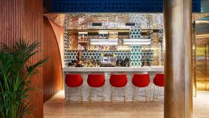 un bar con taburetes rojos frente a un mostrador en Kimpton Vividora Hotel, an IHG Hotel en Barcelona