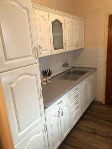 uma cozinha com armários brancos e um lavatório em Bakonyi Mamutfenyő Vendégház em Tés