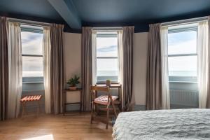 a bedroom with two windows and a desk and a bed at Selina Brighton in Brighton & Hove