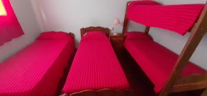 três beliches num quarto com lençóis cor-de-rosa em Hospedaje Alva Suar em Gasoducto