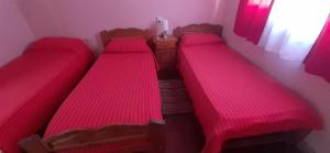 trzy łóżka w pokoju z czerwoną pościelą w obiekcie Hospedaje Alva Suar w mieście Gasoducto