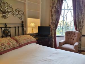 a bedroom with a bed and a chair and a television at Stow Lodge Hotel in Stow on the Wold