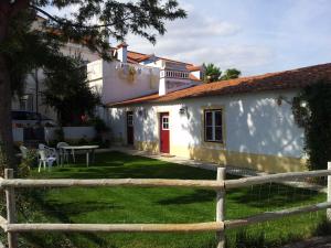 une maison blanche avec une porte rouge et une clôture dans l'établissement Casa da Tia Guida, à Golegã