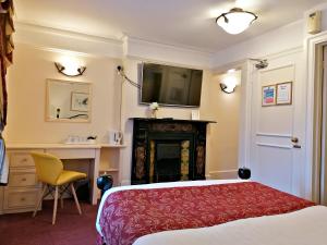 a bedroom with a bed and a fireplace and a television at The Gordon House Hotel in Rochester