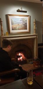 a man sitting in a chair in front of a fireplace at Stow Lodge Hotel in Stow on the Wold