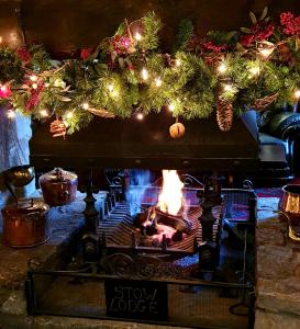 a stove with a fire in a room with christmas decorations at Stow Lodge Hotel in Stow on the Wold