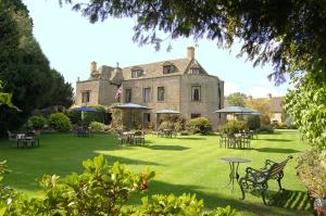 a large house with tables and chairs in the yard at Stow Lodge Hotel in Stow on the Wold