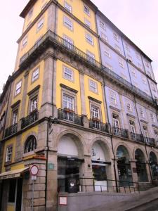 a tall yellow building with windows on a street at Ribeira do Porto Hotel in Porto