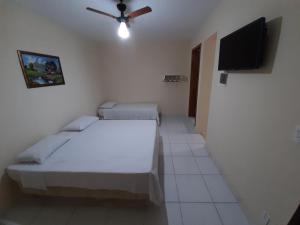 a room with two beds and a flat screen tv at Pousada Pena in Aparecida