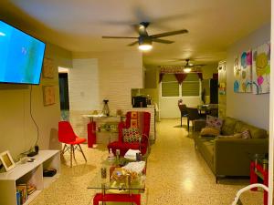 a living room with a green couch and red chairs at Cozy Beach Apartment in Luquillo