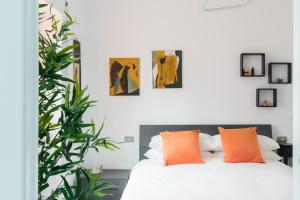 una camera da letto con un letto bianco e cuscini arancioni di Amoretti Apartment, 6 persone, 3 camere, 2 bagni, balcone, Wi-Fi, Metro B Monti Tiburtini a Roma