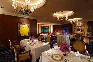 a dining room with white tables and chairs with flowers on them at ANA Crowne Plaza Hotel Kyoto by IHG in Kyoto