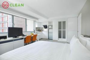 - une chambre blanche avec un lit et un bureau avec une télévision dans l'établissement Wilby Central Serviced Apartments, à Singapour