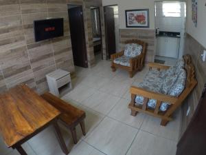 una sala de estar con mesas y sillas de madera. en cabo frio barato, en Cabo Frío