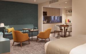a hotel room with a bed and a couch and chairs at Staybridge Suites London Heathrow - Bath Road, an IHG Aparthotel in Hillingdon