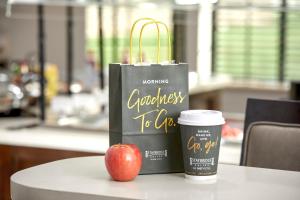 a bag and an apple and a cup of coffee on a table at Staybridge Suites - Miami International Airport by IHG in Miami