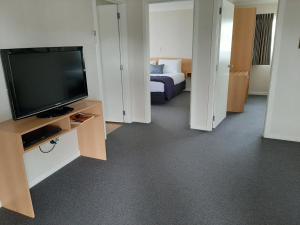 Habitación de hotel con TV y cama en Central Motor Lodge, en Morrinsville