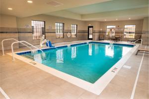 uma piscina num hotel com uma mulher sentada à beira dele em Staybridge Suites - Washington DC East - Largo, an IHG Hotel em Largo