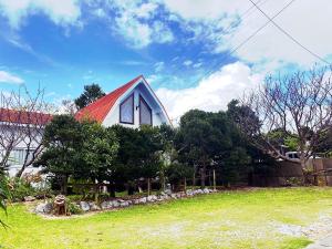 una casa con techo rojo en la parte superior de un patio en 来家 Motobu Kuruchi 美ら海水族館すぐの蝶々がいつでも観察できる貸別荘, en Motobu