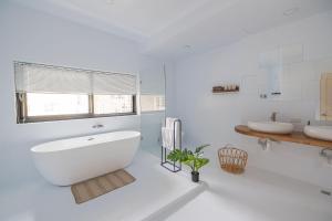 a white bathroom with a tub and two sinks at The Cave in Tainan