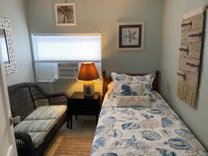 a bedroom with a bed and a lamp and a window at Across bridge to Palm Beaches! Great Price for 3 Bedroom House! Sleeps 5 Fenced Backyard Deck Grill Firepit!Close to Downtown in Lake Worth