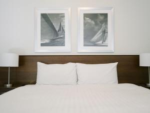 2 fotografías enmarcadas sobre una cama con 2 almohadas blancas en Somerset on the Pier Hobart, en Hobart