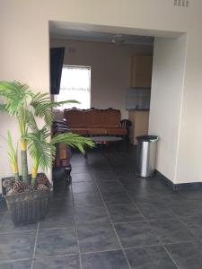 a living room with a couch and palm trees at Henry's House On Sea in Hibberdene