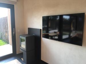 una grande TV a schermo piatto su un muro accanto a una finestra di Beau Réveil nature & wellness - gite 1 a Manhay