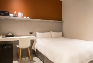 a bedroom with a bed and a desk and a chair at Cityinn Hotel Taipei Station Branch I in Taipei