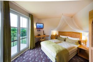 a hotel room with a bed and a large window at Akzent Waldhotel Rheingau in Geisenheim