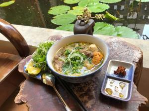 un tazón de sopa en una mesa con un plato de comida en Leranda Homestay, en Hue