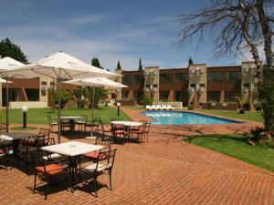 eine Terrasse mit Tischen und Sonnenschirmen neben einem Pool in der Unterkunft Welkom Inn in Welkom