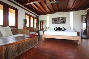 ein Schlafzimmer mit einem Bett und einem Sofa in einem Zimmer in der Unterkunft Twin Island Villas & Dive Resort in Nusa Lembongan