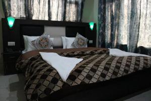 a bedroom with a large bed with black and white comforter at Hotel Samar in Srinagar